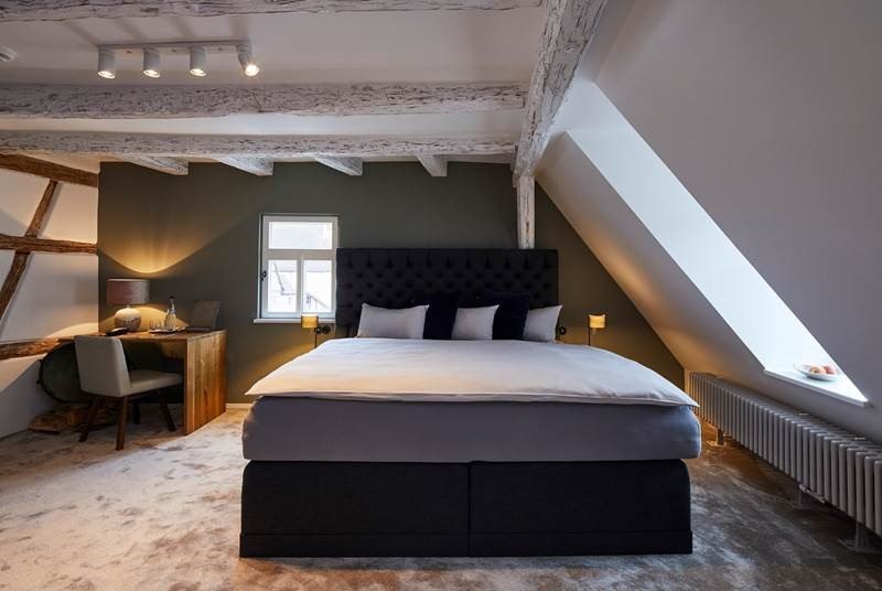 Gem&uuml;tliches Schlafzimmer mit sichtbaren Holzbalken, gro&szlig;em Bett, Schreibtisch und Dachfenster. Die W&auml;nde sind in dunklem Gr&uuml;n gehalten., &copy; Hotel Restaurant Bachofer