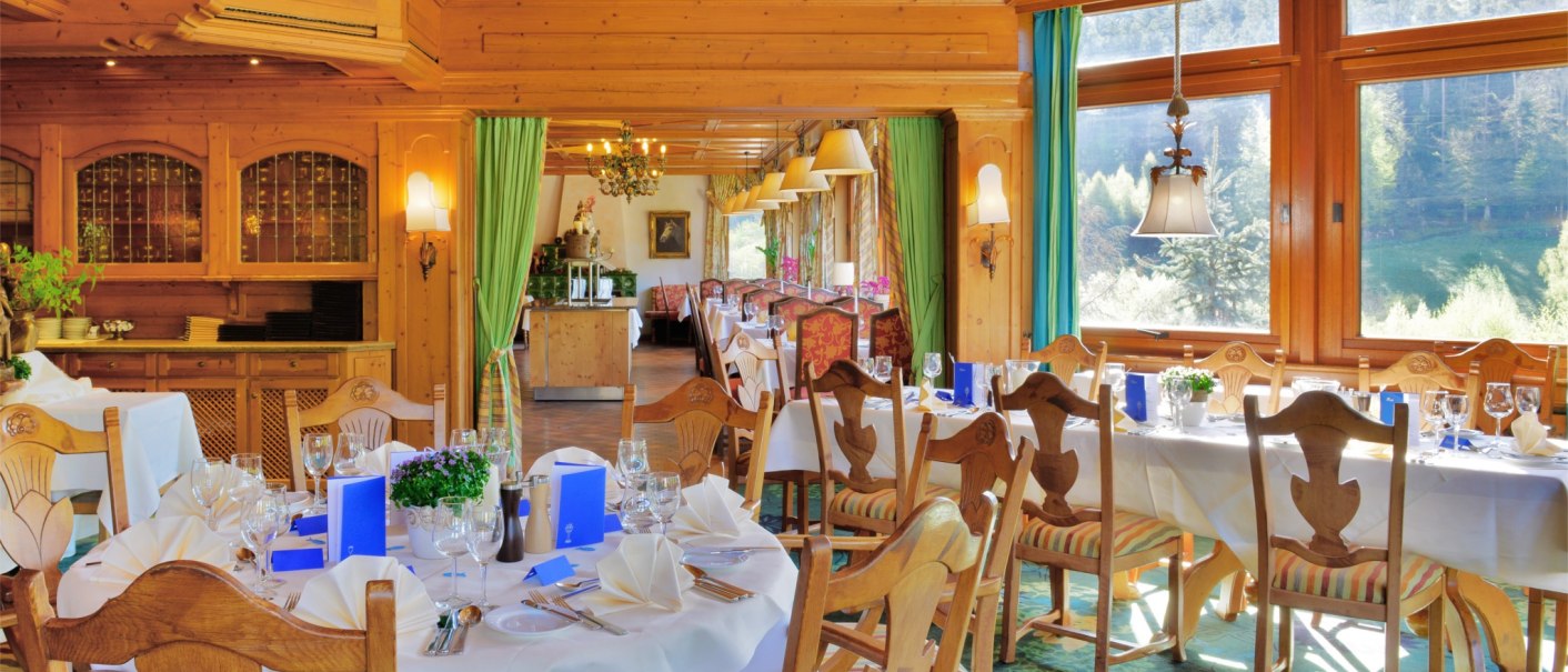 Elegant restaurant with wooden furnishings, laid tables and large windows overlooking the countryside. Inviting atmosphere with chandeliers., © TOMAS
