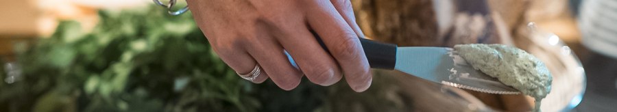 A hand with a wristband takes cream of mushroom from a bowl. Next to it are bowls of herb cream cheese and paprika cream, with bread in the background., &copy; Caf&eacute; Justus, Stuttgart