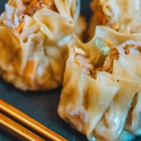 Close-up of steamed dumplings with chopsticks on a plate. The dumplings are filled and have a light, shiny surface., &copy; C&auml;ff Chen, Stuttgart