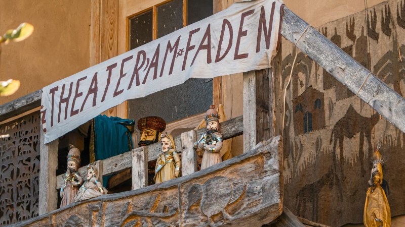 A wooden balcony with puppets and a hand-painted banner 'Theater am Faden'. The puppets are traditionally dressed., © SMG Stuttgart Marketing GmbH - Sarah Schmid