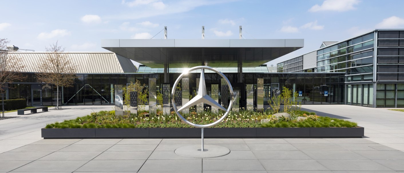 The Mercedes-Benz Customer Center with a large Mercedes logo in the foreground, surrounded by modern architecture and plants., © Mercedes-Benz Kundencenter