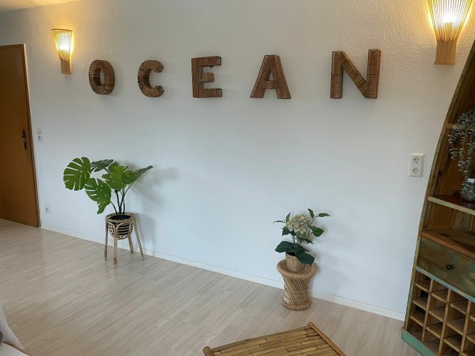 Bright room with wooden floor, plants in baskets and the word 'OCEAN' in wooden letters on the wall., © Cool-Tours StattReisen Bright room with wooden floor, plants in baskets and the word 'OCEAN' in wooden letters on the wall., © Cool-Tours StattReisen
