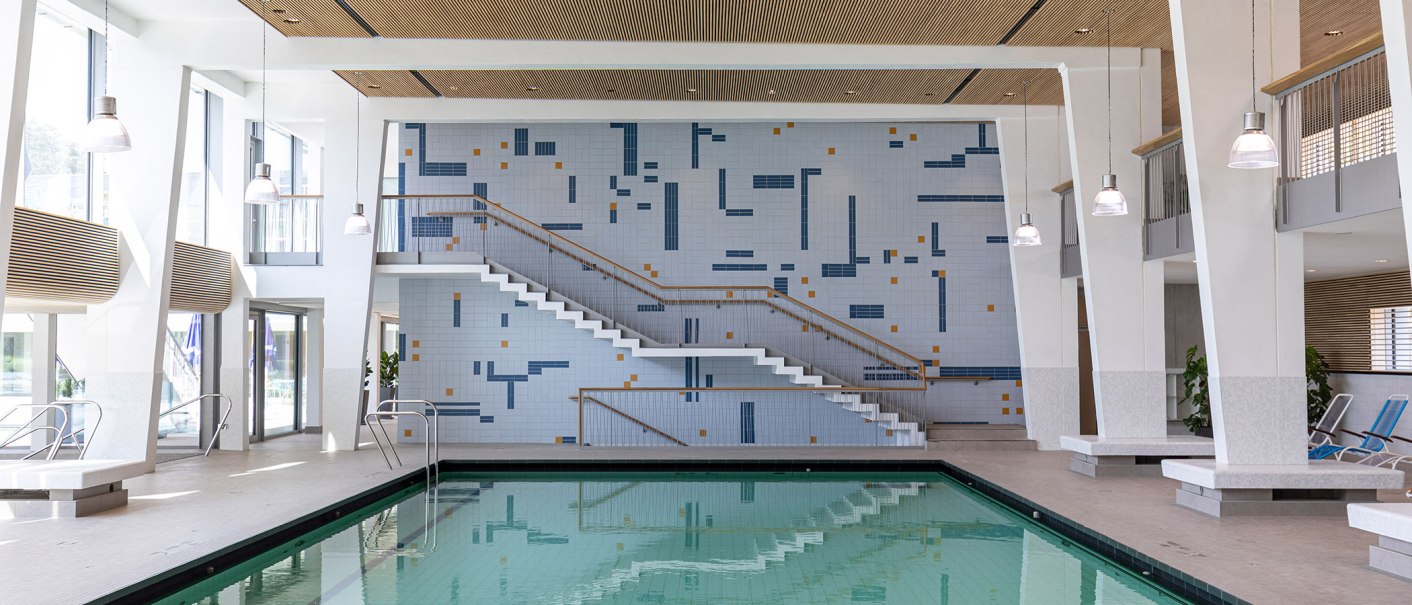 Modern swimming pool with rectangular pool, steps and mosaic wall. Bright lighting and large windows create a friendly atmosphere., © Stuttgarter Bäder