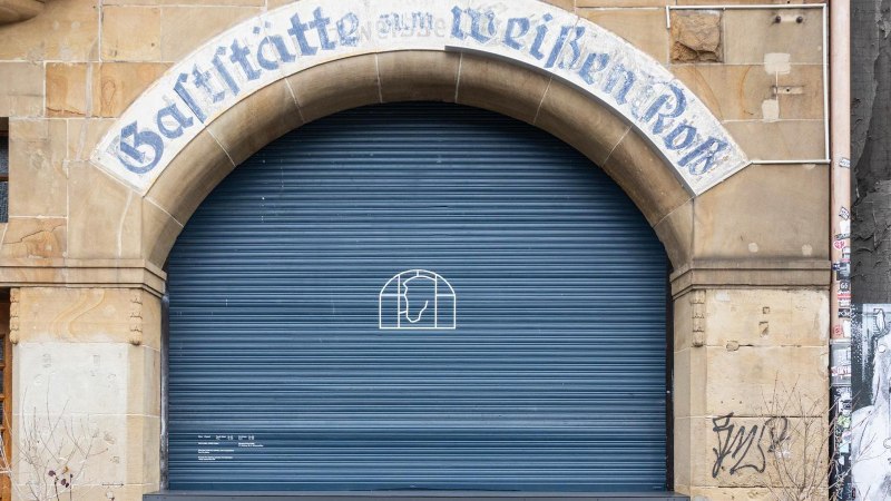 Entrance with the inscription 'Gastst&auml;tte zum wei&szlig;en Ro&szlig;' above a blue roller shutter. Next to it is a wooden door with a 'Card Only' sign., &copy; Stuttgart-Marketing GmbH, Sarah Schmid