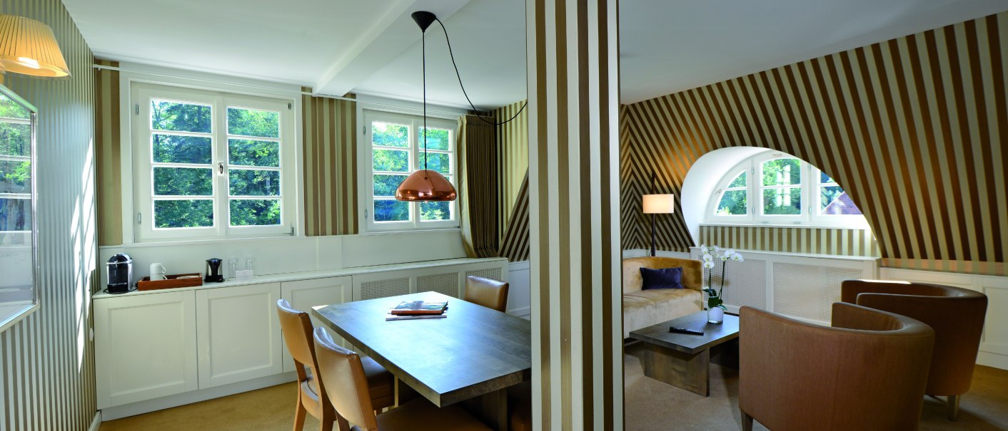 Elegante Suite im Waldhotel Stuttgart mit gestreiften Wänden, Esstisch, Sesseln und großen Fenstern. Helle und stilvolle Einrichtung., © Waldhotel Stuttgart GmbH