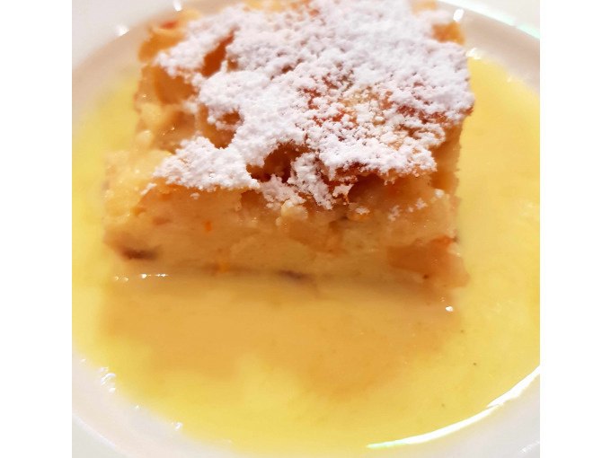 Ein Stück Kuchen mit Puderzucker bestreut, serviert auf einem Teller mit Vanillesoße., © Kultweine-Kochwelten-Kunstücke - Kochschule Sonja Lenz Ein Stück Kuchen mit Puderzucker bestreut, serviert auf einem Teller mit Vanillesoße., © Kultweine-Kochwelten-Kunstücke - Kochschule Sonja Lenz