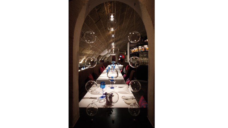 Elegantes Restaurant mit langer Tafel, dekoriert mit blauen Gläsern und schwebenden Glaskugeln., © Délice, Stuttgart Elegantes Restaurant mit langer Tafel, dekoriert mit blauen Gläsern und schwebenden Glaskugeln., © Délice, Stuttgart