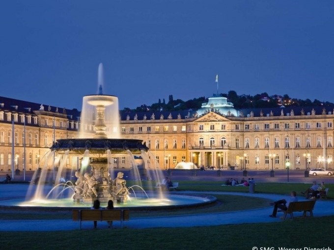 Das Neue Schloss in Stuttgart bei Nacht, beleuchtet mit einem gro&szlig;en Brunnen im Vordergrund. Menschen sitzen auf B&auml;nken und genie&szlig;en die Atmosph&auml;re., &copy; Stuttgart Marketing GmbH