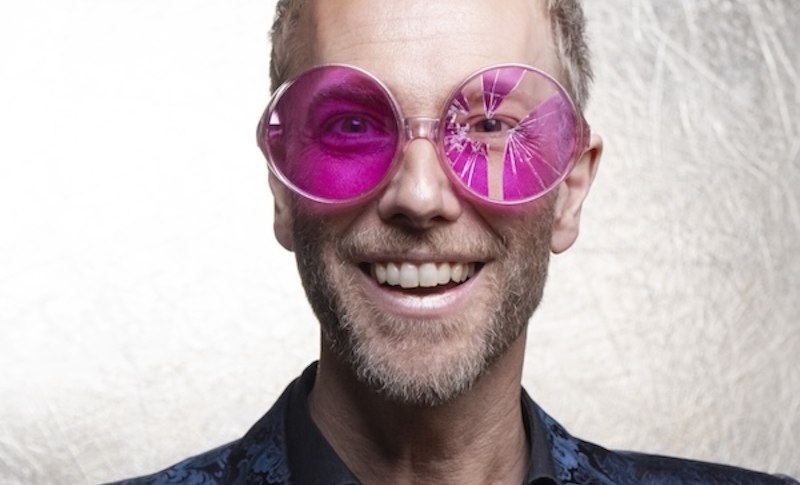 Ein Mann tr&auml;gt eine gro&szlig;e, pinke Brille und ein blau gemustertes Jackett vor einem hellen Hintergrund., &copy; Renitenztheater Stuttgart e.V.