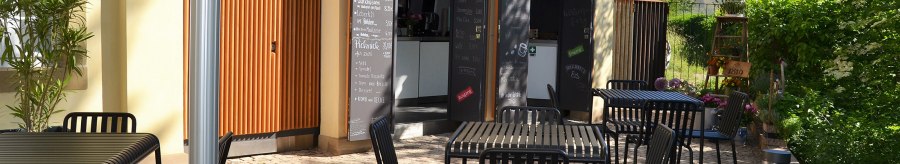 Outdoor area of the 1819 Bistro am Wirtemberg with black tables and chairs on paved ground, surrounded by green vegetation., © 1819 Bistro am Wirtemberg