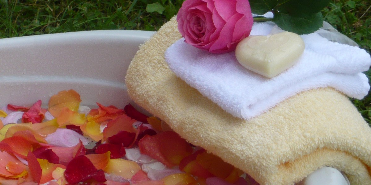 Rose petals in a bowl with towels, a rose and heart-shaped soap for a wellness experience., &copy; Hotel Hochwald