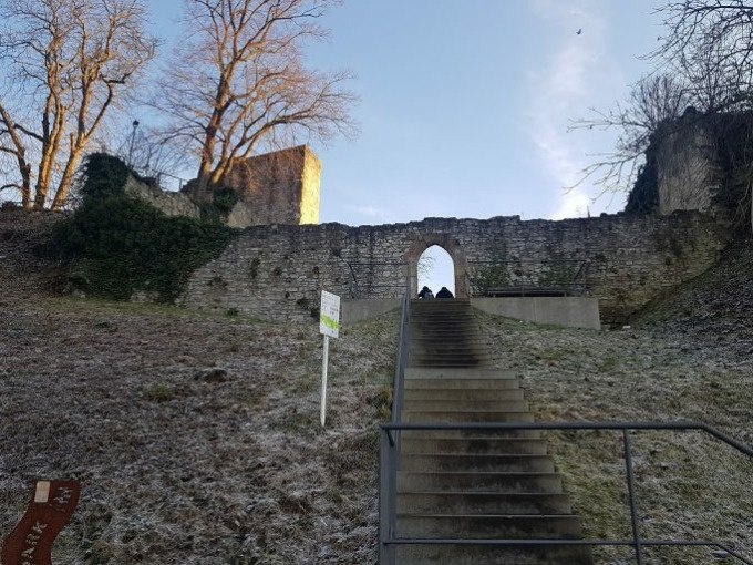 Steintreppe führt zu einer alten Burgmauer mit Torbogen, umgeben von kahlen Bäumen und leichtem Frost., © Cool-Tours StattReisen Steintreppe führt zu einer alten Burgmauer mit Torbogen, umgeben von kahlen Bäumen und leichtem Frost., © Cool-Tours StattReisen