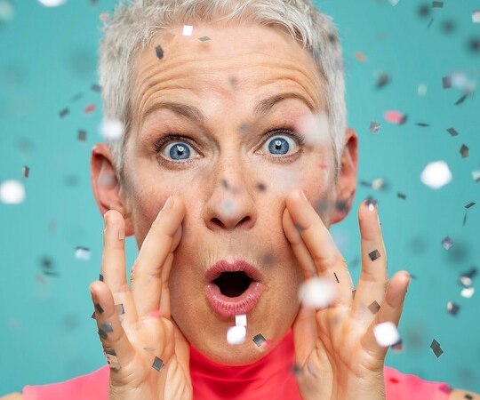 Person mit kurzem Haar und überraschter Mimik, umgeben von Konfetti vor blauem Hintergrund., © Renitenztheater Stuttgart e.V. Person mit kurzem Haar und überraschter Mimik, umgeben von Konfetti vor blauem Hintergrund., © Renitenztheater Stuttgart e.V.