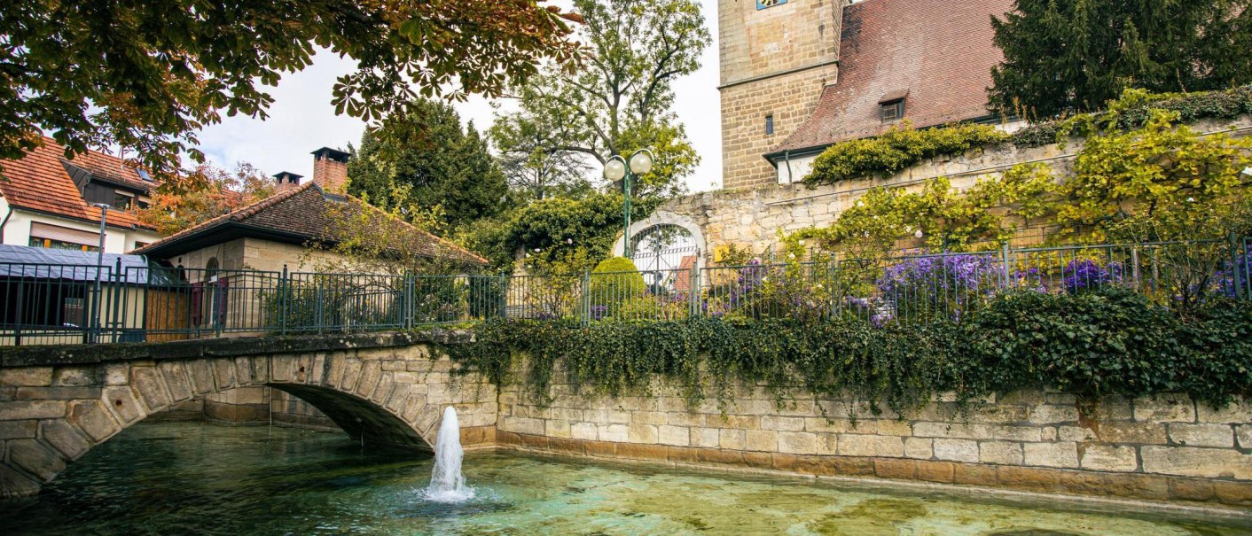 An idyllic view of the town center of Echterdingen with a stone bridge, a fountain and a historic tower in the background., © Stuttgart-Marketing GmbH, Sarah Schmid