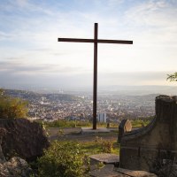 A cross on the Birkenkopf in Stuttgart, surrounded by rubble, with a view of the city in the background at sunset., © Stuttgart-Marketing GmbH, Jean-Claude Winkler A cross on the Birkenkopf in Stuttgart, surrounded by rubble, with a view of the city in the background at sunset., © Stuttgart-Marketing GmbH, Jean-Claude Winkler