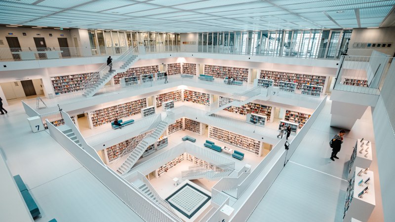 Moderne, helle Bibliothek mit mehreren Etagen, weißen Wänden und Bücherregalen. Menschen bewegen sich auf den Treppen und lesen Bücher., © Stuttgart-Marketing GmbH, Sarah Schmid Moderne, helle Bibliothek mit mehreren Etagen, weißen Wänden und Bücherregalen. Menschen bewegen sich auf den Treppen und lesen Bücher., © Stuttgart-Marketing GmbH, Sarah Schmid