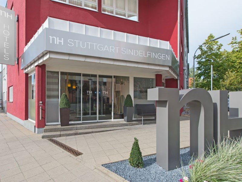 Eingang des NH Hotels in Stuttgart Sindelfingen mit roter Fassade, großem Logo und Pflanzen., © NH Stuttgart Sindelfingen Eingang des NH Hotels in Stuttgart Sindelfingen mit roter Fassade, großem Logo und Pflanzen., © NH Stuttgart Sindelfingen