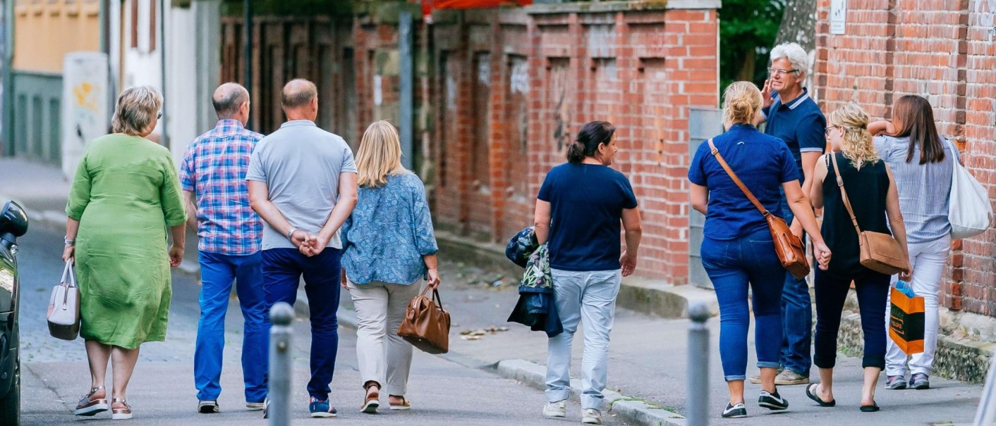 Gruppe von Menschen spaziert entlang einer Backsteinmauer in der Stadt., © Thomas Niedermüller