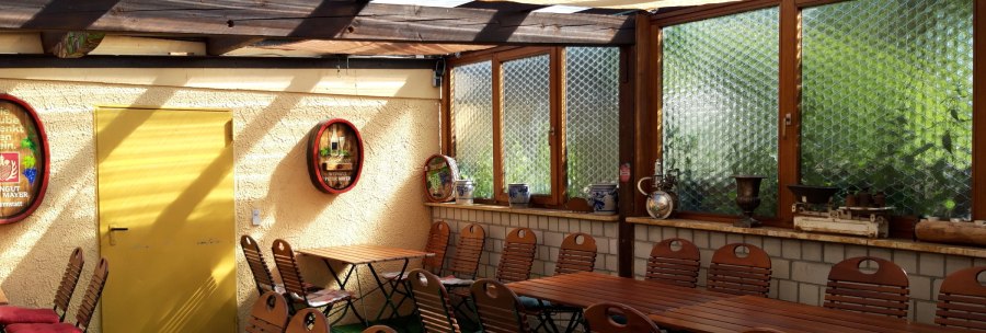 Cozy wine bar with wooden tables and chairs, yellow door, decorative barrels and windows with glass bricks., &copy; Weinstube J&auml;gerhof