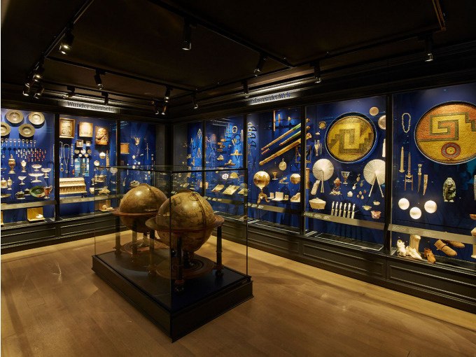 Museum exhibition with antique objects in display cases, including two large globes. The walls are illuminated in blue., &copy; Landesmuseum W&uuml;rttemberg