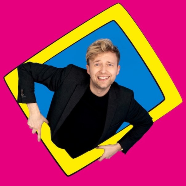 A man in a black suit smiles through a yellow frame on a blue background, surrounded by a pink background., &copy; Renitenztheater Stuttgart e.V.