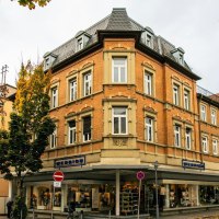 Historic buildings in the center of Göppingen, surrounded by autumnal trees. A store with shop windows and street signs are visible., © Stuttgart-Marketing GmbH, Sarah Schmid