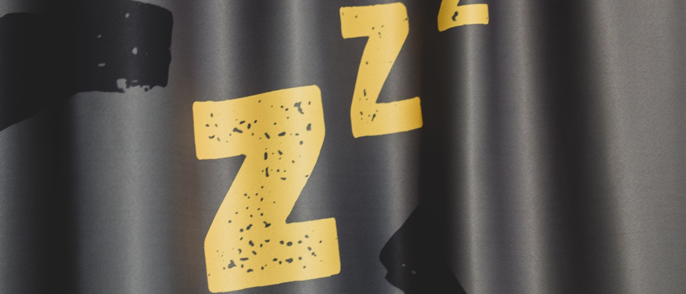 Gelbe Zzz auf schwarzem Hintergrund, symbolisieren Schlaf oder Ruhe. Die Buchstaben sind groß und auffällig gestaltet., © Das Schlafwerk - DQuadrat Living GmbH
