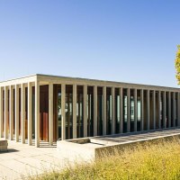 A modern building with a glass facade and columns, surrounded by trees and a meadow under a clear sky., &copy; SMG Stuttgart Marketing GmbH - Sarah Schmid