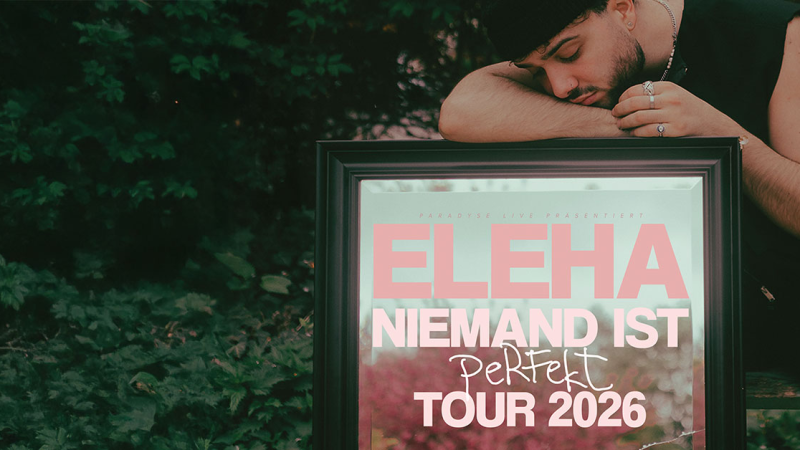 Ein Mann lehnt seinen Kopf auf einen Bilderrahmen mit der Aufschrift 'ELEHA - Niemand ist perfekt Tour 2026'. Der Hintergrund ist gr&uuml;n und bewaldet., &copy; links im Bild