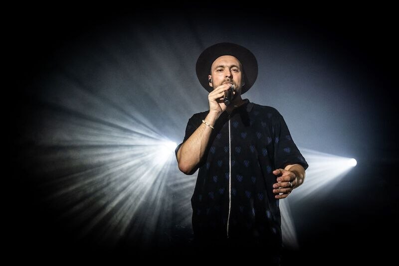 A singer in a hat performs on a stage while beams of light dramatically illuminate him., © Music Circus Concertbüro GmbH &CoKG A singer in a hat performs on a stage while beams of light dramatically illuminate him., © Music Circus Concertbüro GmbH &CoKG