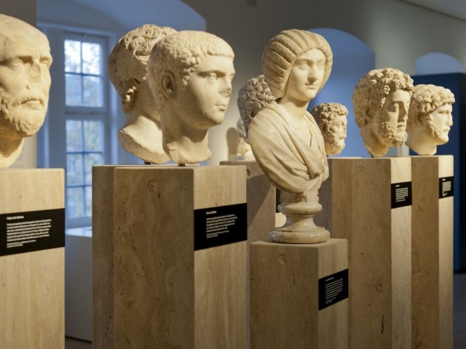 Eine Reihe antiker Marmorb&uuml;sten auf Sockeln in einem Museum, die im warmen Licht ausgestellt sind. Die B&uuml;sten zeigen verschiedene historische Figuren., &copy; Landesmuseum W&uuml;rttemberg
