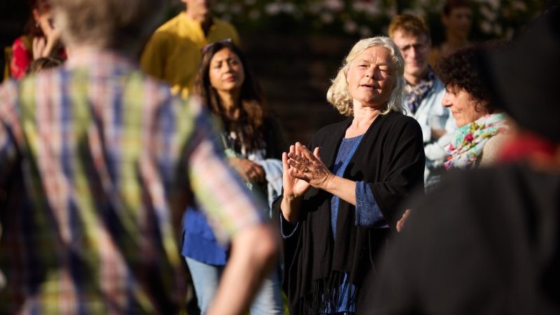 Eine Frau spricht zu einer Gruppe von Menschen im Freien. Sie trägt einen schwarzen Schal und gestikuliert mit den Händen. Die Zuhörer sind aufmerksam., © Ars Narrandi e. V. Eine Frau spricht zu einer Gruppe von Menschen im Freien. Sie trägt einen schwarzen Schal und gestikuliert mit den Händen. Die Zuhörer sind aufmerksam., © Ars Narrandi e. V.