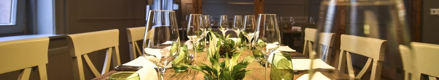 A stylishly laid dining table with wine glasses, green glasses and plants as decoration in an elegant room., &copy; Classic Rock Caf&eacute; Gastronomie- Betriebs GmbH