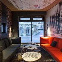 Modern room with gray and red sofas, chessboard pattern on table, wall with chess pieces, window with view of building., &copy; TOMAS