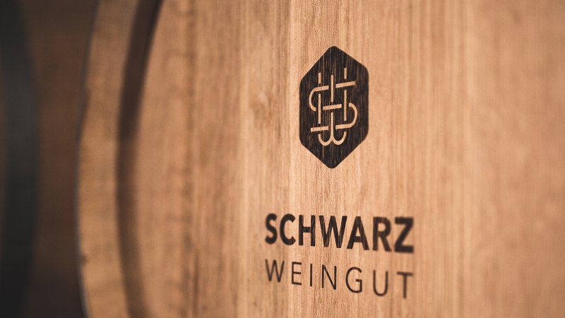 Wooden barrel with the logo and lettering 'Schwarz Weingut', close-up., © Weingut Schwarz