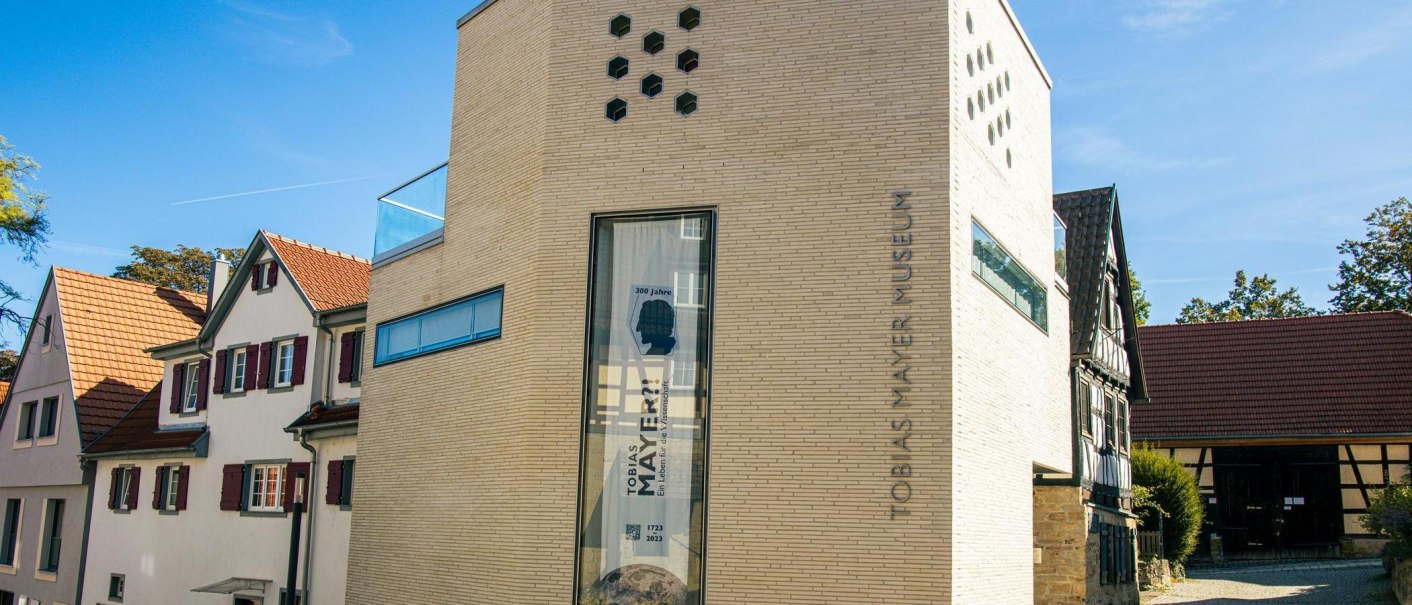 Das Tobias-Mayer-Museum in Marbach am Neckar zeigt eine moderne Fassade neben traditionellen Fachwerkhäusern unter blauem Himmel., © Stuttgart-Marketing GmbH, Sarah Schmid Das Tobias-Mayer-Museum in Marbach am Neckar zeigt eine moderne Fassade neben traditionellen Fachwerkhäusern unter blauem Himmel., © Stuttgart-Marketing GmbH, Sarah Schmid
