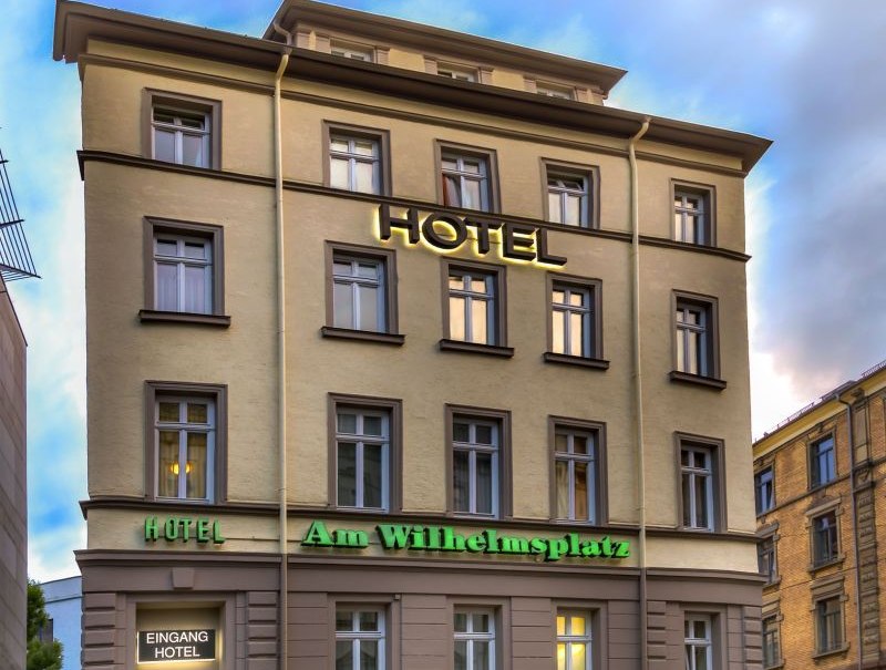 Multi-storey hotel with the sign 'Hotel Am Wilhelmsplatz', a parked car in front of it. The sky is cloudy., &copy; TOMAS