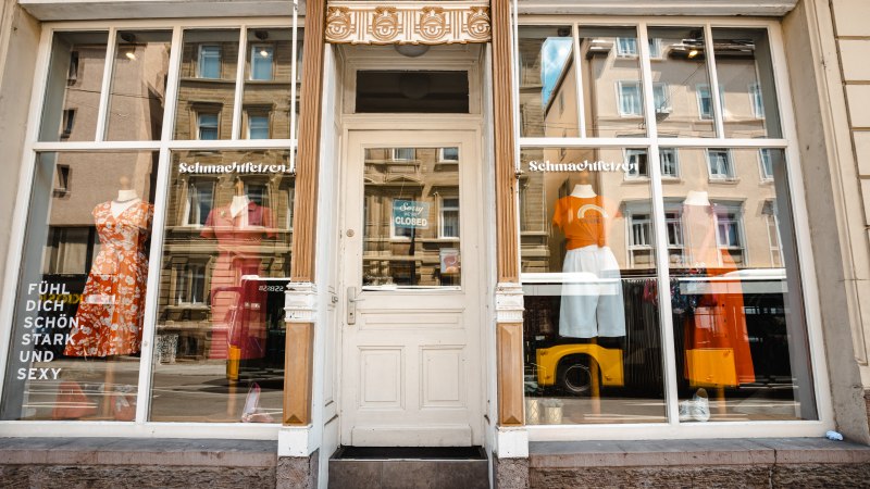Schaufenster eines Modegeschäfts namens 'Schmachtfetzen' mit bunten Kleidern und einem Schild 'Sorry, we are closed' an der Tür., © SMG Stuttgart Marketing GmbH - Sarah Schmid Schaufenster eines Modegeschäfts namens 'Schmachtfetzen' mit bunten Kleidern und einem Schild 'Sorry, we are closed' an der Tür., © SMG Stuttgart Marketing GmbH - Sarah Schmid