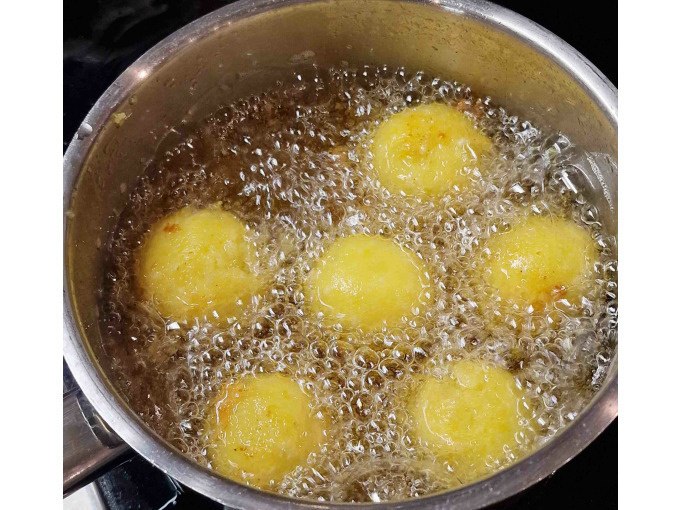 Sechs goldbraune Teigb&auml;llchen werden in einem Topf mit sprudelndem &Ouml;l frittiert. Die Oberfl&auml;che ist knusprig und gleichm&auml;&szlig;ig gebr&auml;unt., &copy; Kultweine-Kochwelten-Kunst&uuml;cke - Kochschule Sonja Lenz