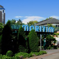 Außenansicht des Maritim Hotels mit markantem Glasdach und umgeben von Bäumen und Pflanzen. Ein Weg führt am Gebäude entlang., © Maritim Hotelgesellschaft mbH