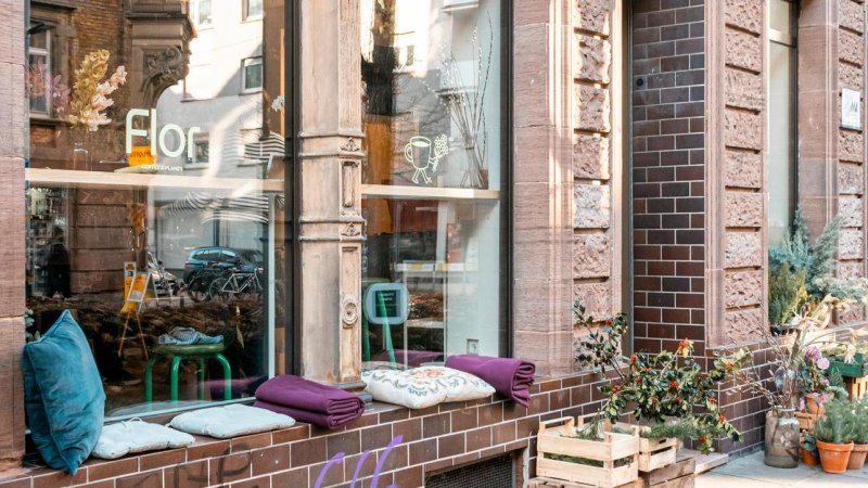 Ein gem&uuml;tliches Caf&eacute; mit Pflanzen und Sitzkissen vor dem Fenster. Die Fassade ist aus Backstein, und es gibt Blumenarrangements auf dem Gehweg., &copy; Stuttgart-Marketing GmbH, Sarah Schmid