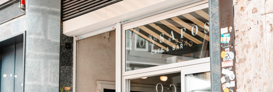 Entrance to a café with the inscription 'ConSafos Café & Bar' on the glass door. Next to it, a wall with stickers., © SMG Stuttgart Marketing GmbH - Sarah Schmid