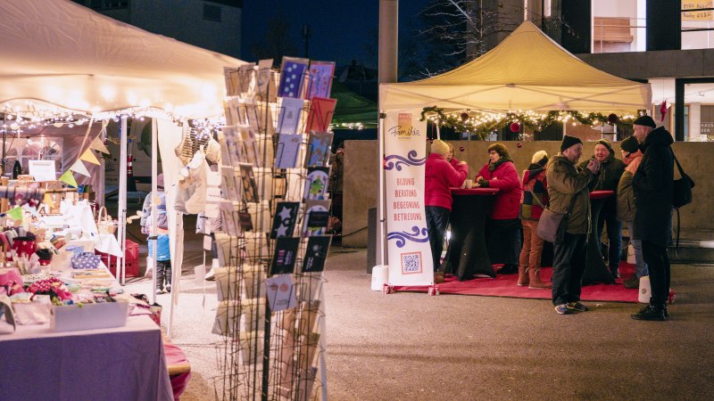 Weihnachtsmarkt in Stuttgart mit beleuchteten Ständen und Menschen, die sich unterhalten. Ein Stand bietet Karten an, ein anderer hat ein Schild mit "Haus der Familie"., © Haus der Familie in Stuttgart e.V. Weihnachtsmarkt in Stuttgart mit beleuchteten Ständen und Menschen, die sich unterhalten. Ein Stand bietet Karten an, ein anderer hat ein Schild mit "Haus der Familie"., © Haus der Familie in Stuttgart e.V.