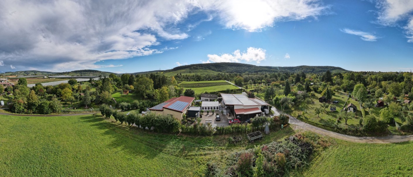 Luftaufnahme des Weinguts Eißele mit Gebäuden, Feldern und Bäumen. Im Hintergrund Hügel und blauer Himmel mit Wolken., © Weingut Eißele Luftaufnahme des Weinguts Eißele mit Gebäuden, Feldern und Bäumen. Im Hintergrund Hügel und blauer Himmel mit Wolken., © Weingut Eißele