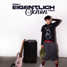 Ein junger Mann steht lässig neben einem Verstärker und einer Gitarre, hält einen Blumenstrauß. Oben ist der Schriftzug 'Rowli - Eigentlich schön Tour' zu sehen., © links im Bild
