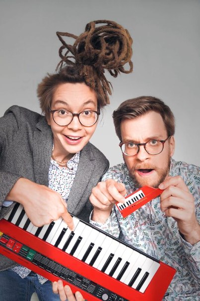 Two people with glasses pose cheerfully with a red keyboard and a miniature keyboard. The scene is humorous and creative., &copy; Rosenau Kultur e.V.