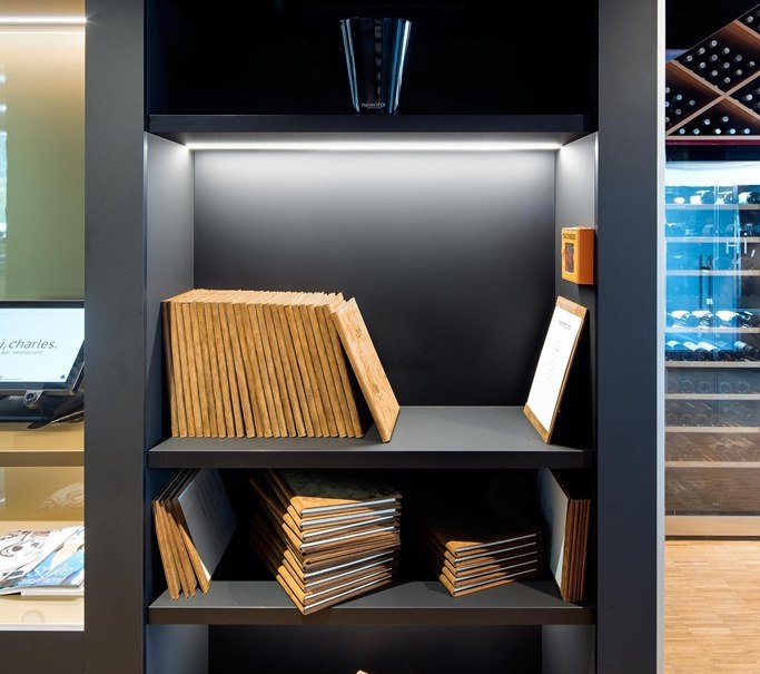A shelf with champagne bottles on top and stacked menus below in a modern restaurant setting., &copy; Hotel am Remspark