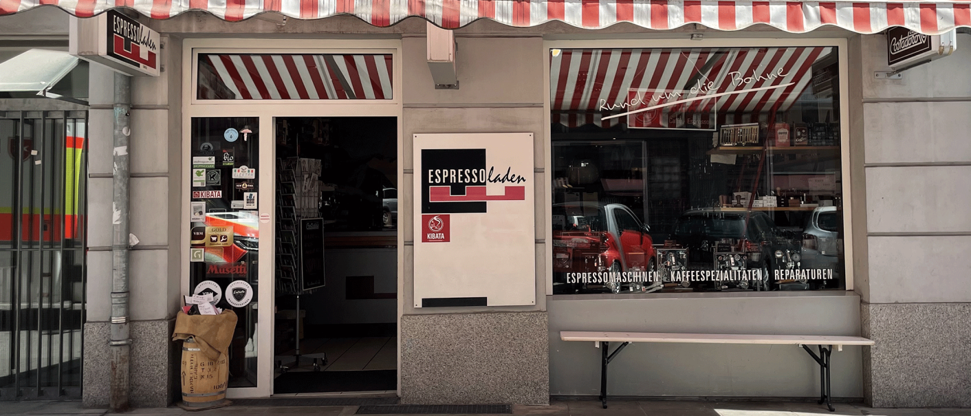 Espressoladen in Stuttgart-Süd mit rot-weiß gestreifter Markise, Schaufenster und Eingangstür. Aufkleber und Kaffeesäcke sind sichtbar., © Espressoladen, Stuttgart