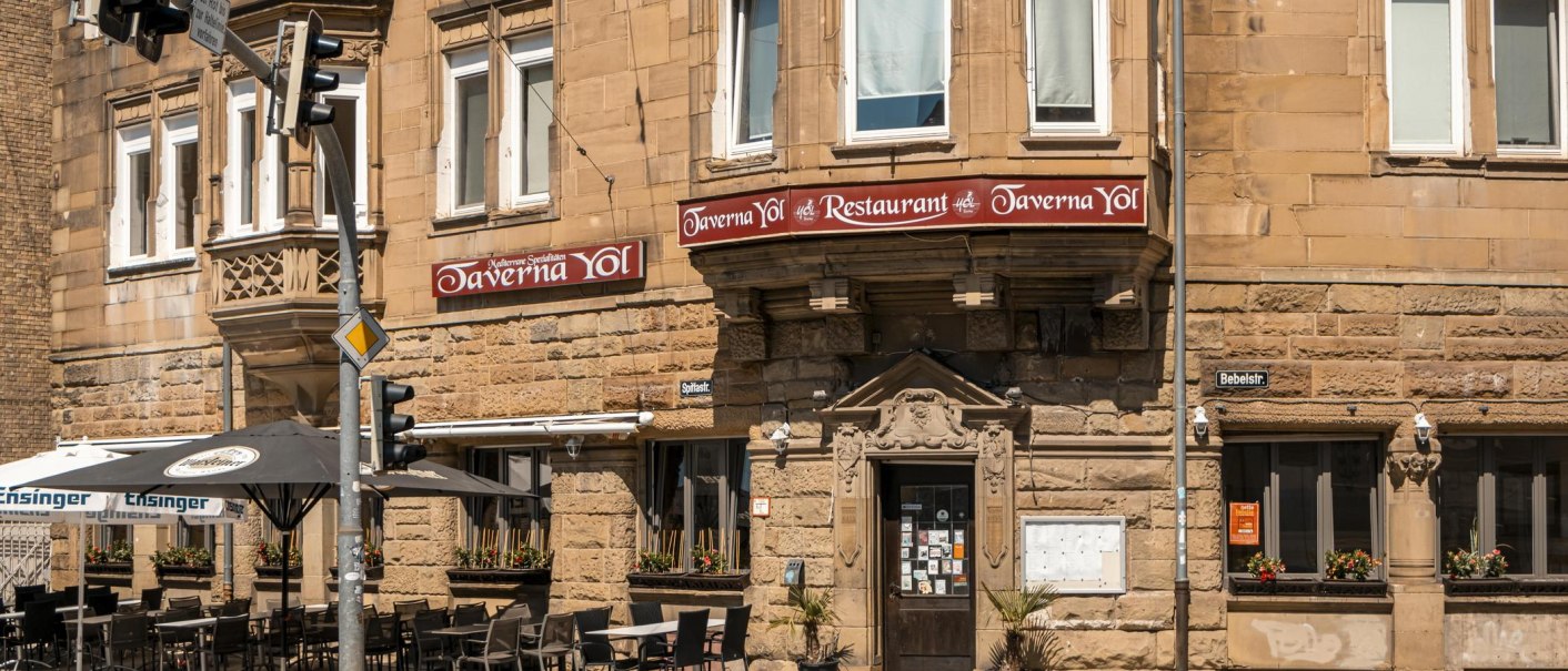 Historisches Geb&auml;ude mit Restaurant Taverna Yol, Sitzpl&auml;tze im Freien, Stra&szlig;enschilder und Ampeln. Sonniger Tag, Blumen in Fenstern., &copy; SMG, Sarah Schmid